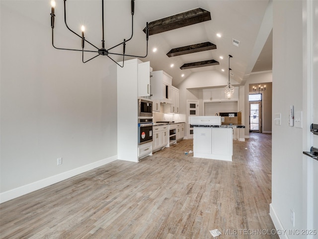 kitchen with white cabinets, appliances with stainless steel finishes, a kitchen island, decorative light fixtures, and a notable chandelier