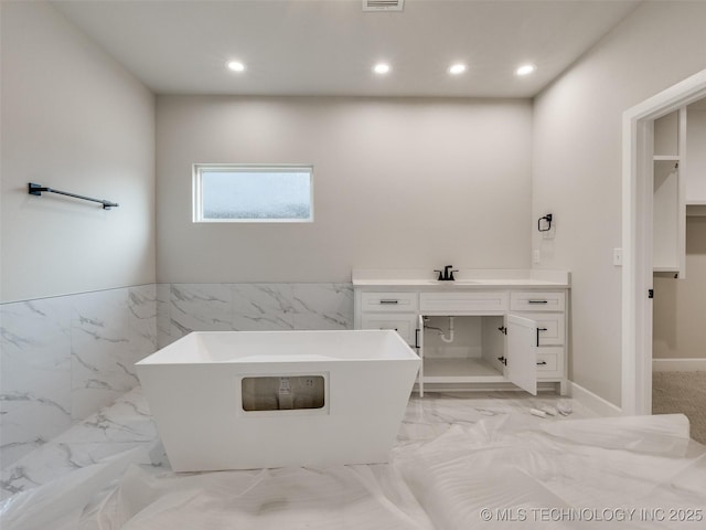 bathroom featuring a washtub, tile walls, and vanity