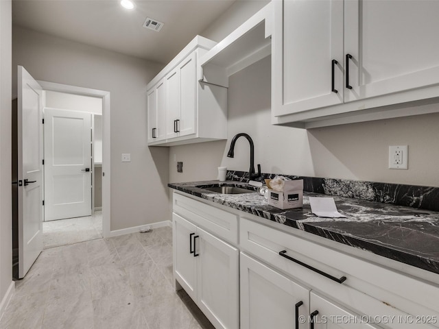 kitchen featuring sink, white cabinetry, and dark stone countertops