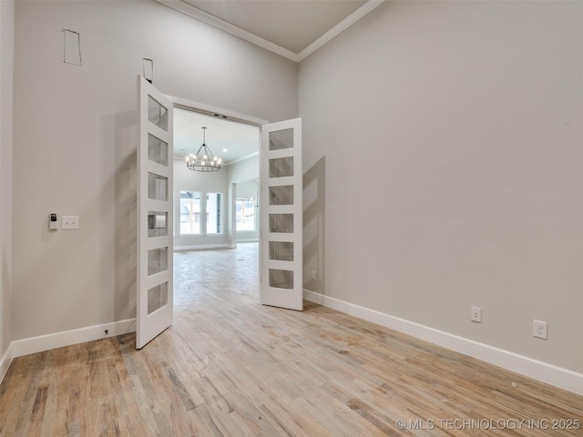 unfurnished room with french doors, crown molding, a chandelier, and hardwood / wood-style flooring