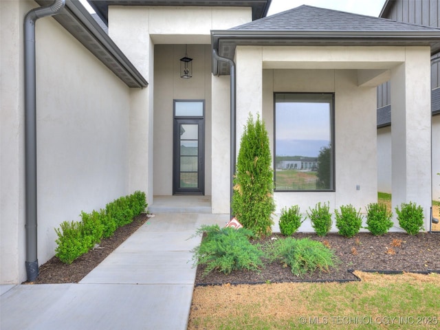 entrance to property with roof with shingles and stucco siding
