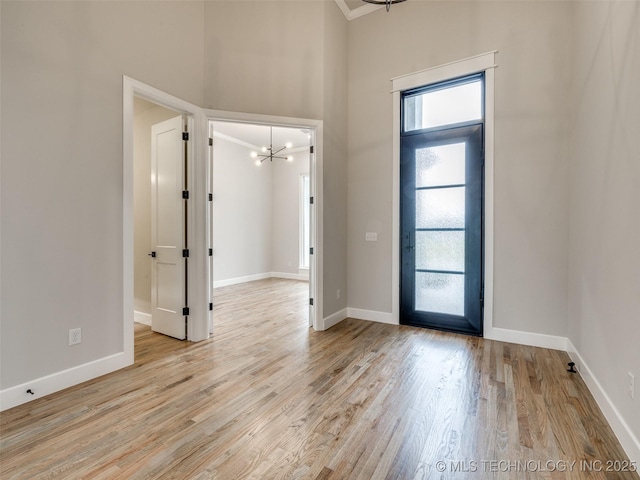 foyer featuring baseboards, an inviting chandelier, a high ceiling, and plenty of natural light