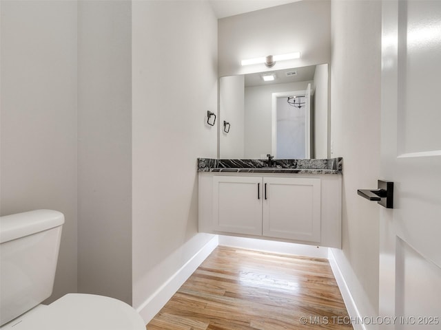 bathroom with wood finished floors, baseboards, vanity, and toilet