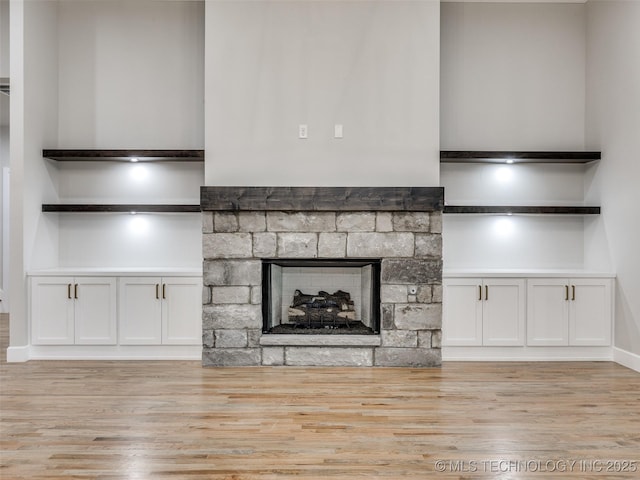 unfurnished living room with a fireplace, light wood-style flooring, and baseboards