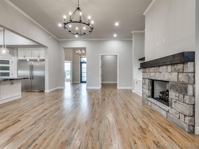 unfurnished living room featuring a chandelier, light wood-style floors, a stone fireplace, and ornamental molding