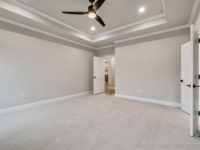 unfurnished bedroom featuring light colored carpet, crown molding, and a tray ceiling