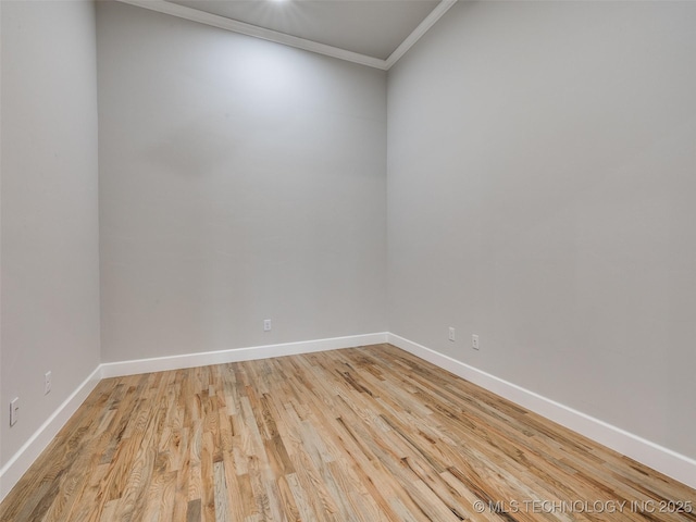 spare room featuring light wood-type flooring, baseboards, and crown molding