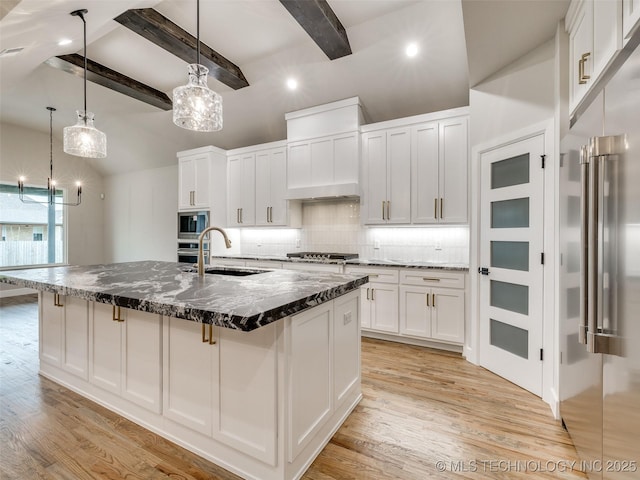 kitchen featuring white cabinets, stainless steel appliances, a sink, light wood-style flooring, and tasteful backsplash