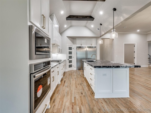 kitchen featuring white cabinets, built in appliances, light wood-style floors, and dark stone counters