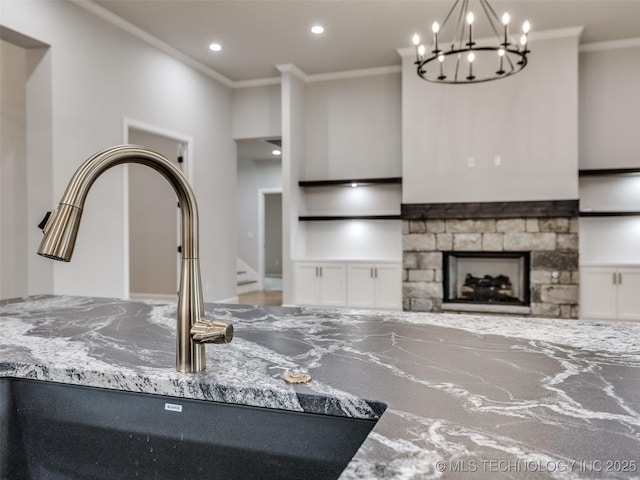 interior space with a sink, an inviting chandelier, stone countertops, ornamental molding, and recessed lighting