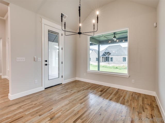unfurnished dining area with wood finished floors, baseboards, lofted ceiling, a notable chandelier, and visible vents