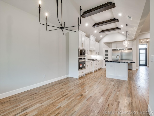 kitchen with a notable chandelier, an island with sink, built in appliances, high vaulted ceiling, and white cabinetry