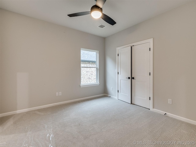 unfurnished bedroom featuring visible vents, a closet, baseboards, carpet flooring, and ceiling fan