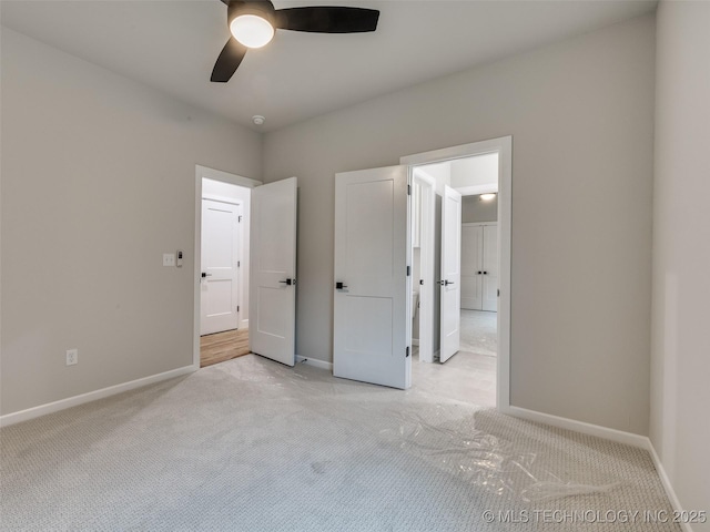 unfurnished bedroom featuring light colored carpet, ceiling fan, and baseboards