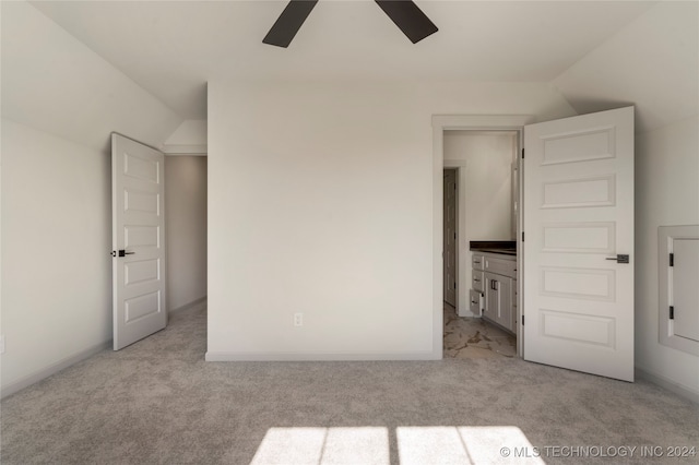 unfurnished bedroom featuring ensuite bath, ceiling fan, light colored carpet, and lofted ceiling