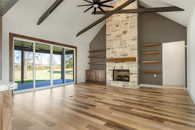 unfurnished living room with high vaulted ceiling, ceiling fan, a fireplace, beamed ceiling, and wood-type flooring