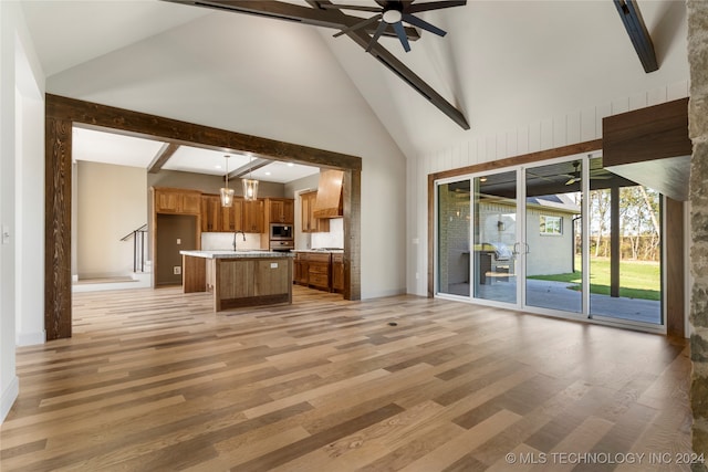 unfurnished living room with beam ceiling, high vaulted ceiling, light hardwood / wood-style flooring, and ceiling fan