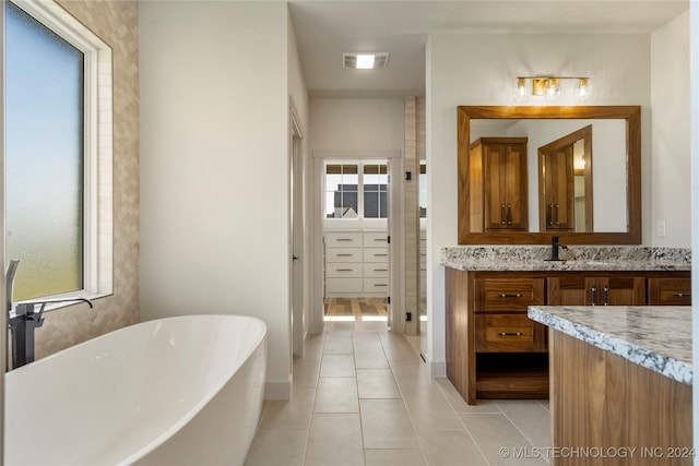 bathroom with tile patterned flooring, vanity, and a tub to relax in