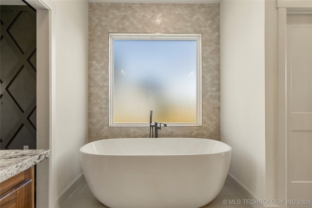 bathroom with a bathing tub, vanity, and tile patterned floors