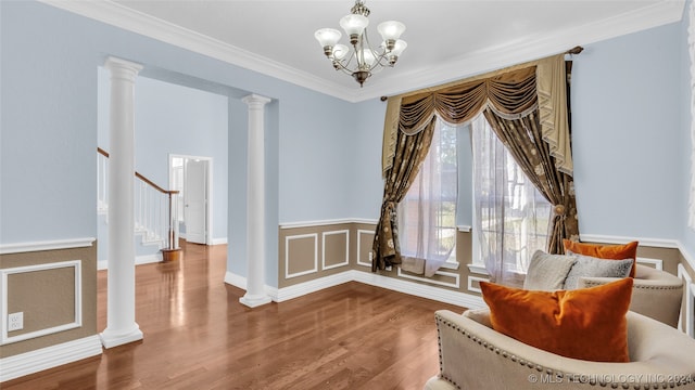 living area featuring hardwood / wood-style floors, decorative columns, crown molding, and a notable chandelier