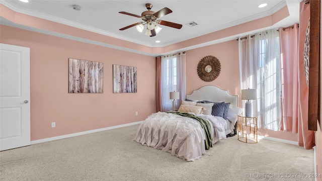 carpeted bedroom featuring ceiling fan, multiple windows, crown molding, and a tray ceiling