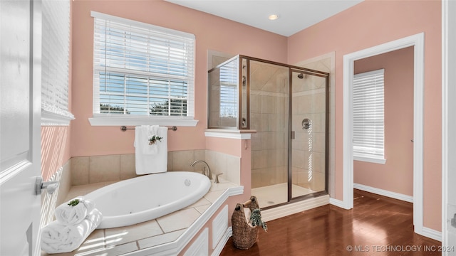 bathroom with wood-type flooring and shower with separate bathtub