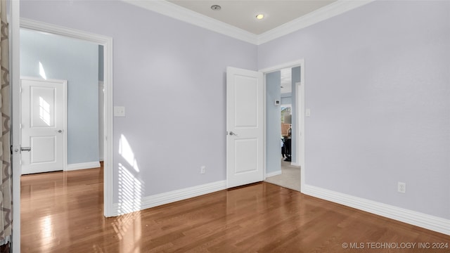 empty room featuring wood-type flooring and ornamental molding