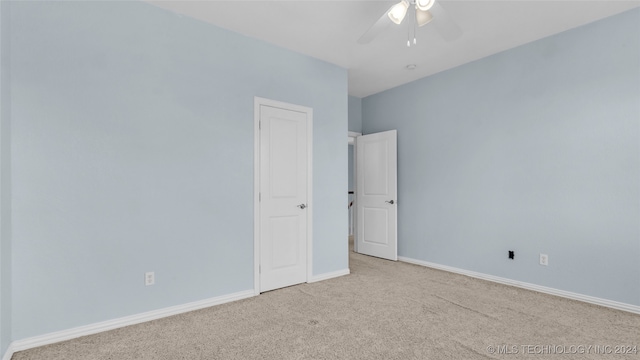 empty room with ceiling fan and light carpet