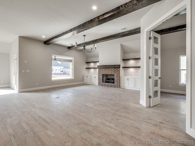 unfurnished living room with built in shelves, beamed ceiling, a brick fireplace, and light wood-type flooring