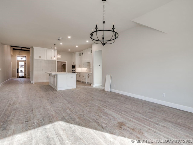 kitchen featuring light hardwood / wood-style flooring, hanging light fixtures, a center island, a notable chandelier, and white cabinets