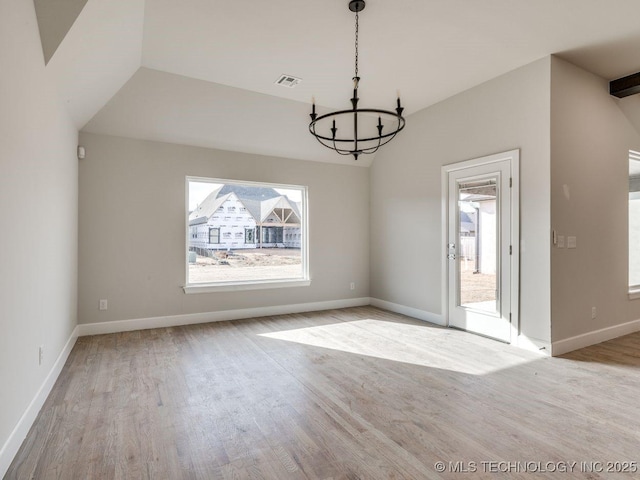 unfurnished dining area featuring an inviting chandelier, vaulted ceiling, and light hardwood / wood-style flooring