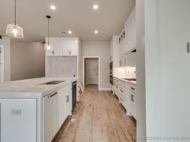 kitchen featuring white cabinetry, black dishwasher, light wood-type flooring, and pendant lighting