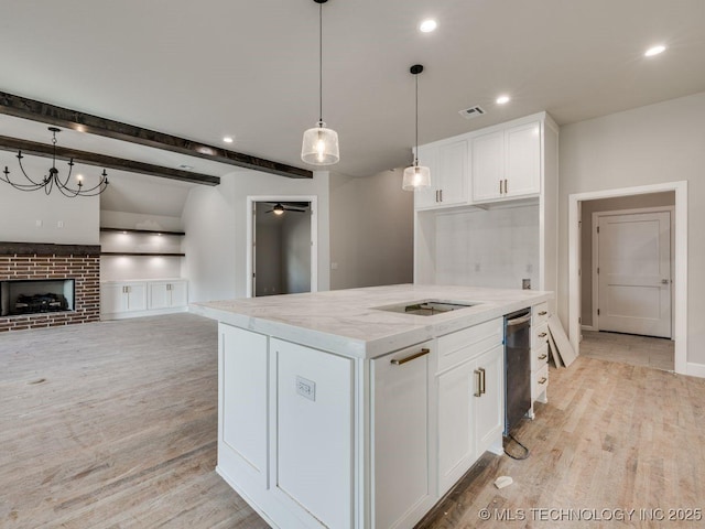 kitchen featuring hanging light fixtures, white cabinetry, light stone countertops, and a fireplace