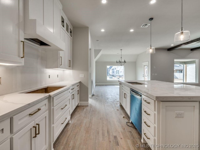 kitchen with white cabinetry, light stone counters, a kitchen island, decorative light fixtures, and stainless steel dishwasher