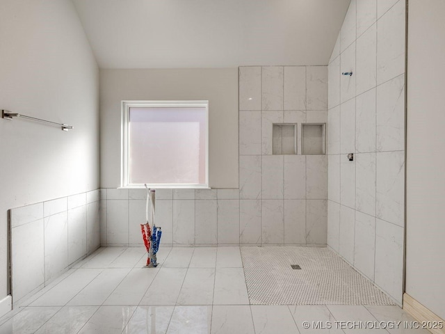 bathroom with a tile shower and vaulted ceiling