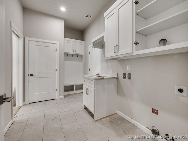 clothes washing area featuring electric dryer hookup, light tile patterned floors, hookup for a washing machine, and cabinets