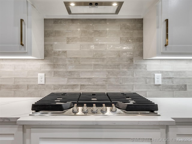 details with white cabinets, light stone counters, stainless steel gas stovetop, and exhaust hood