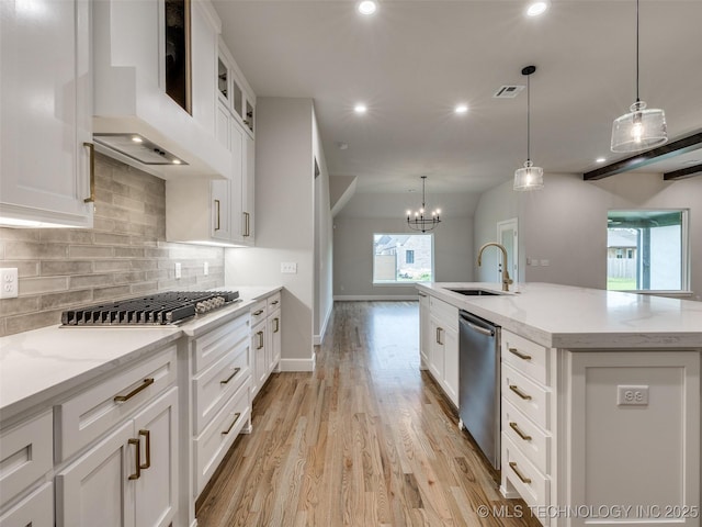 kitchen featuring a sink, stainless steel appliances, backsplash, wall chimney exhaust hood, and visible vents