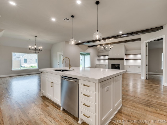 kitchen featuring light wood finished floors, a sink, light stone countertops, a chandelier, and open floor plan
