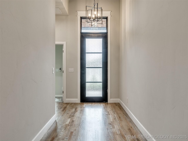 foyer with baseboards, a notable chandelier, and light wood-style flooring