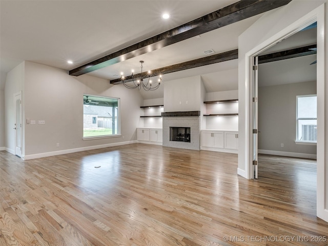 unfurnished living room featuring a chandelier, light wood-style floors, baseboards, and beamed ceiling
