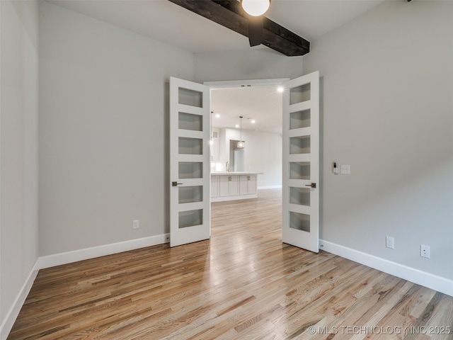 empty room featuring baseboards, french doors, and light wood-style flooring