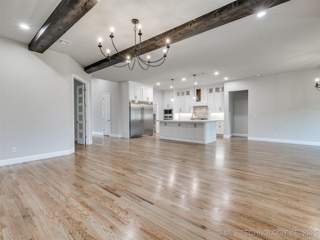 unfurnished living room with a sink, beamed ceiling, a notable chandelier, visible vents, and recessed lighting