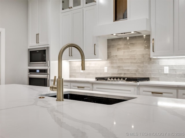 kitchen with custom exhaust hood, a sink, built in microwave, oven, and white cabinets