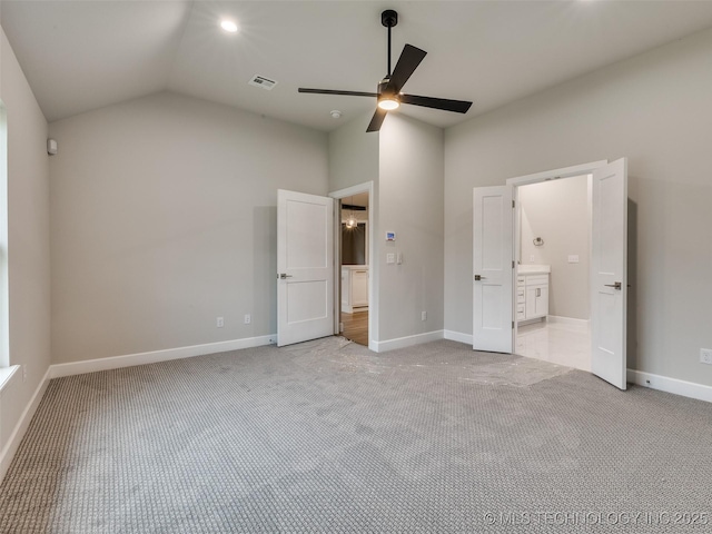 unfurnished bedroom with vaulted ceiling, visible vents, baseboards, light colored carpet, and ensuite bath