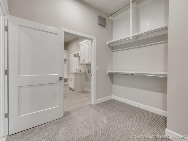 walk in closet featuring light colored carpet