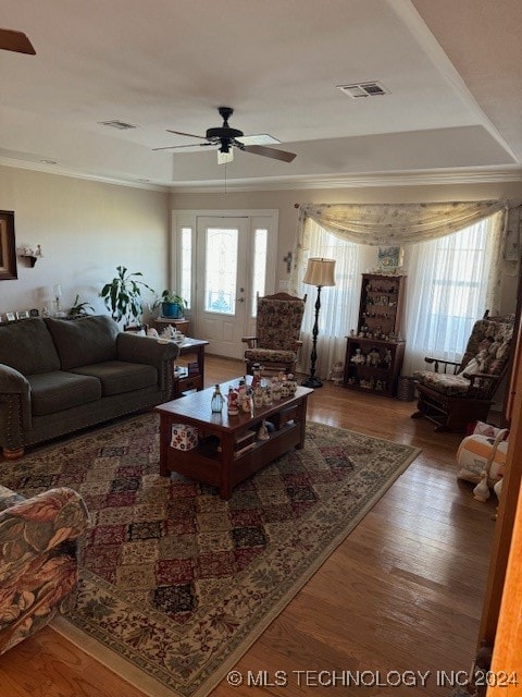 living room featuring ceiling fan, a raised ceiling, and wood-type flooring