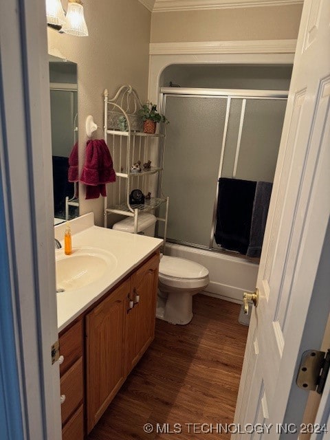 full bathroom with hardwood / wood-style floors, vanity, toilet, ornamental molding, and enclosed tub / shower combo