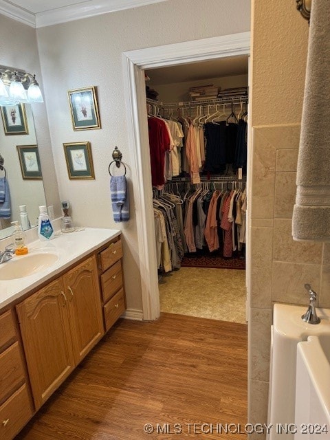 bathroom with hardwood / wood-style flooring, vanity, ornamental molding, and tile walls