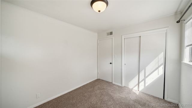 unfurnished bedroom featuring carpet floors, a closet, and crown molding